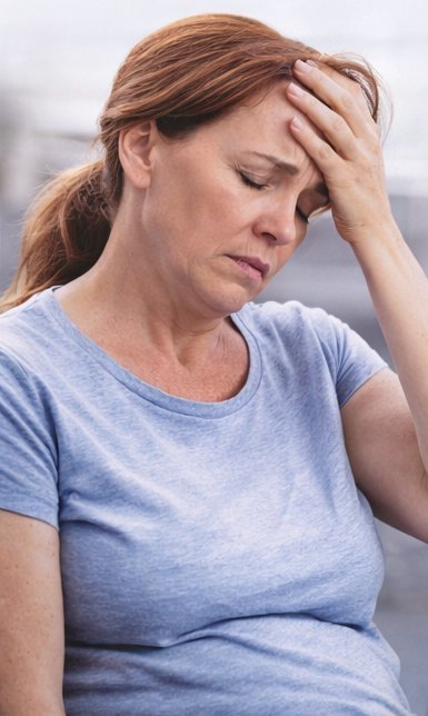 A woman in her sixties standing at her kitchen counter with her hand on her forehead after checking her glucose reading